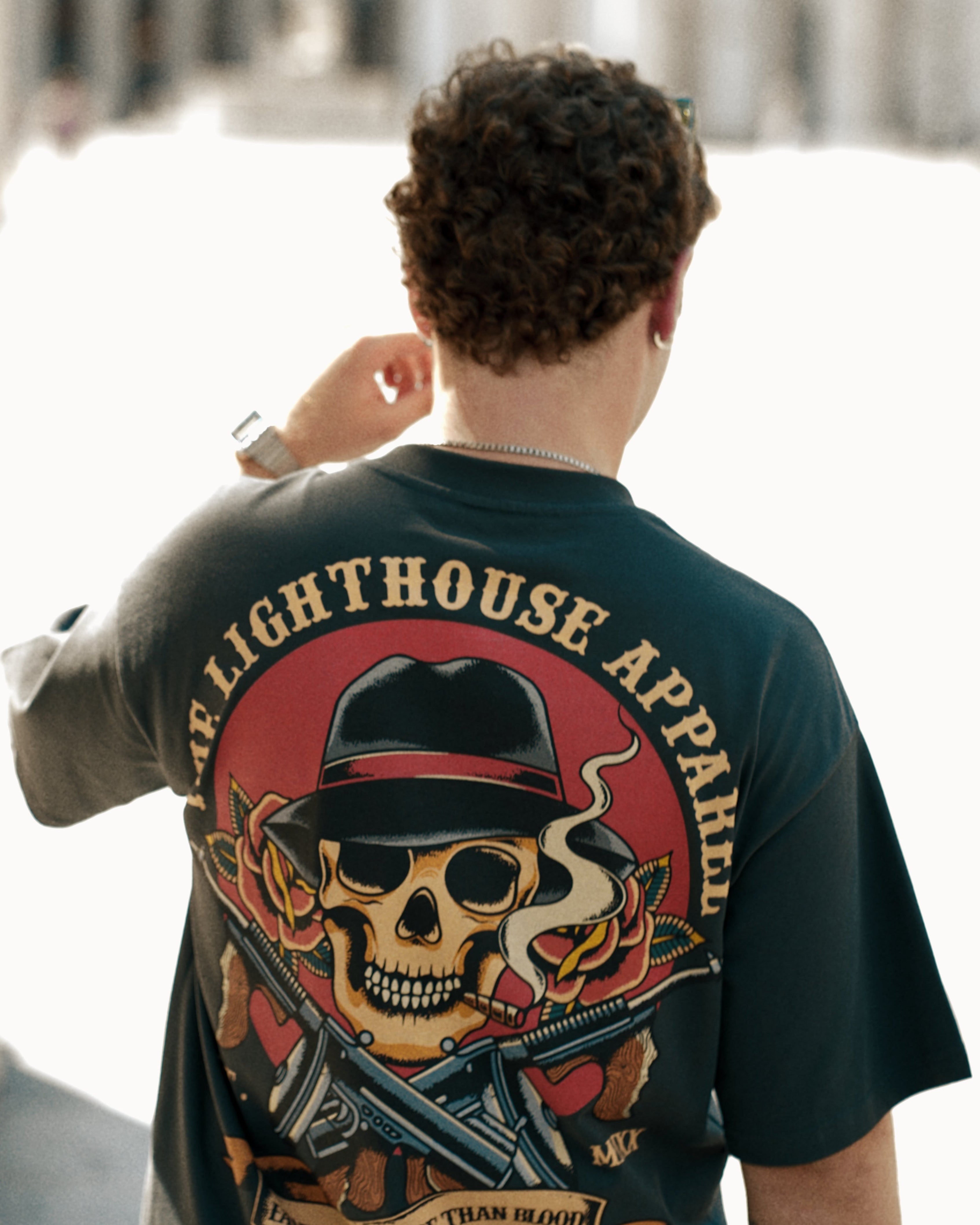 Person wearing a t-shirt with a skull and crossbones design and 'Lighthouse Apparel' branding.